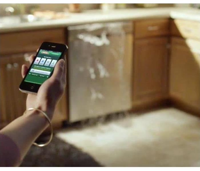 Setting Kitchen. Phone out with SERVPRO emergency plan on home screen. Water over flow from dish washer