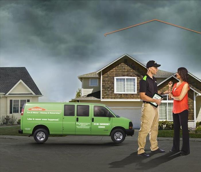Rainy skies, SERVPRO crew talking to customer in front of house. 